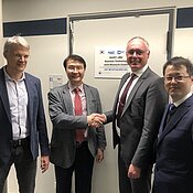 The Principal Investigators (PIs), Prof. Dr. Yong-Hoon Cho and Prof. Sven Höfling, shaking hands after revealing the new joint office with Prof. Dr. Björn Trauzettel and Dr. Jeongwon Lee.