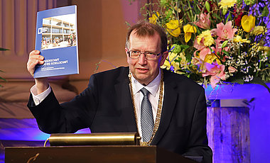 Alfred Forchel zeigt den JMU-Entwicklungsplan "Profil und Perspektiven der Julius-Maximilians-Universität Würzburg".