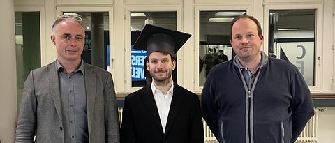 Simon Betzold mit Prof. Dr. Sven Höfling (r.) und Prof. Dr. Sebastian Klembt (l.) im Foyer der Fakultät nach dem Promotionskolloquium.