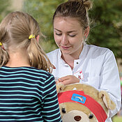 In der Teddyklinik lässt ein Mädchen seinen kranken Teddy behandeln.